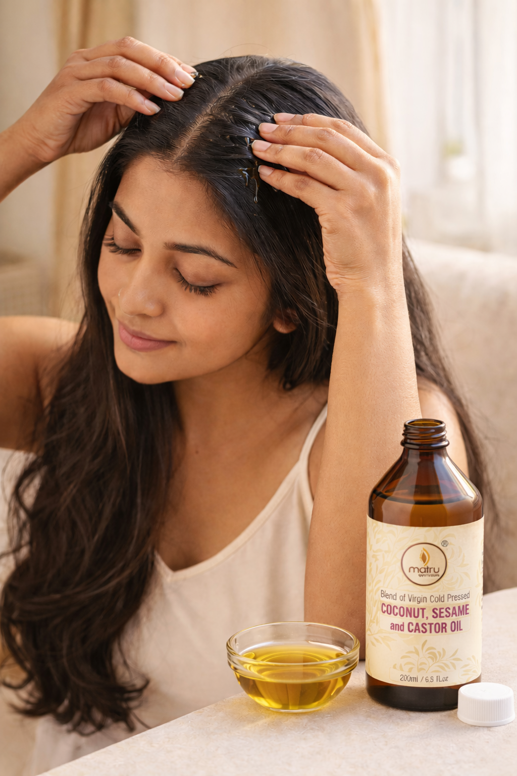 Indian woman applying Matru Ayurveda coconut castor sesame oil blend to scalp for hair growth and hair fall control